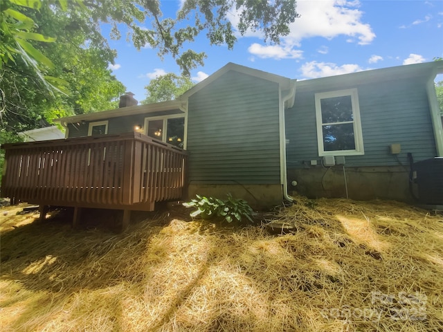 rear view of property featuring a wooden deck and a chimney