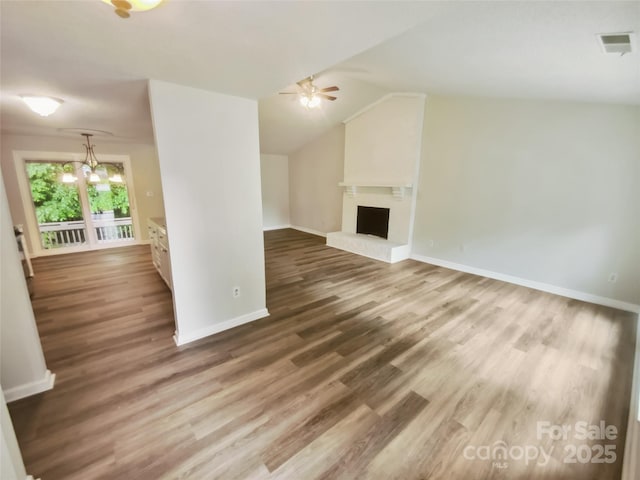 unfurnished living room with a ceiling fan, wood finished floors, baseboards, a fireplace with raised hearth, and lofted ceiling