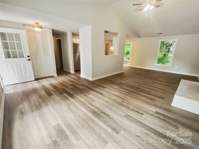 unfurnished living room with ceiling fan, wood finished floors, baseboards, and lofted ceiling