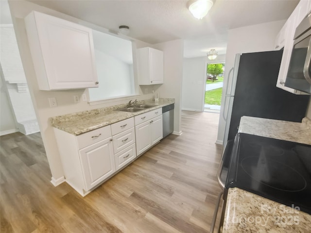 kitchen featuring a sink, stainless steel appliances, baseboards, and white cabinets