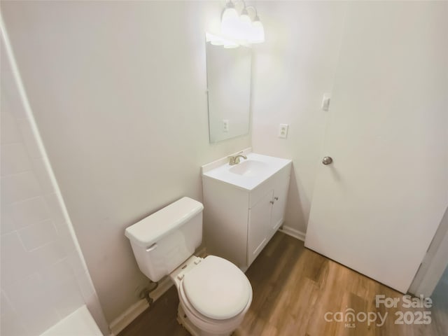 bathroom featuring wood finished floors, vanity, toilet, and a shower