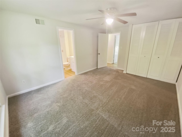 unfurnished bedroom with carpet floors, a closet, baseboards, connected bathroom, and ceiling fan