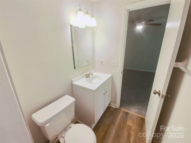 bathroom featuring wood finished floors, vanity, ceiling fan, toilet, and baseboards