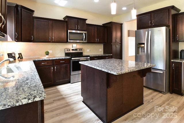 161 Old Harbor Dr, Mount Gilead, NC 27306 - kitchen featuring appliances with stainless steel finishes, a sink, light wood finished floors, a kitchen island, and dark brown cabinets
