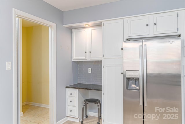111 Clubwood Ct, Asheville, NC 28803 - kitchen featuring stainless steel fridge with ice dispenser, white cabinetry, dark stone counters, light tile patterned floors, and baseboards