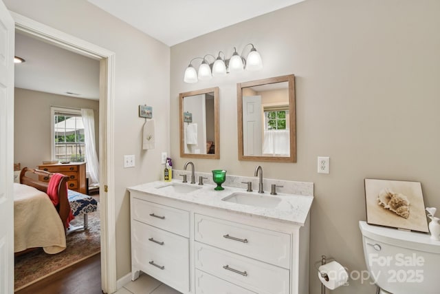 full bath with ensuite bathroom, double vanity, toilet, and baseboards
