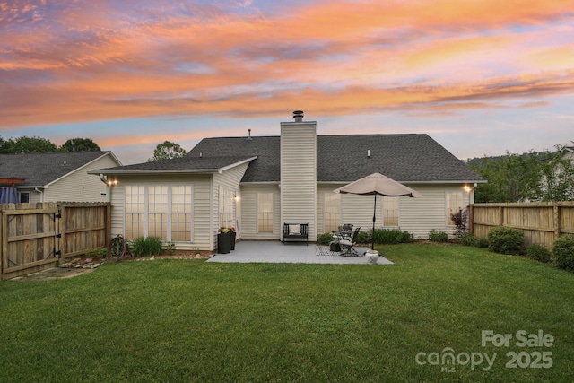 back of house at dusk featuring a patio area, a chimney, and a shingled roof