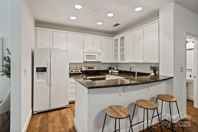 400 N Church St Unit 226, Charlotte, NC 28202 - kitchen featuring white appliances, wood finished floors, a sink, glass insert cabinets, and dark stone counters