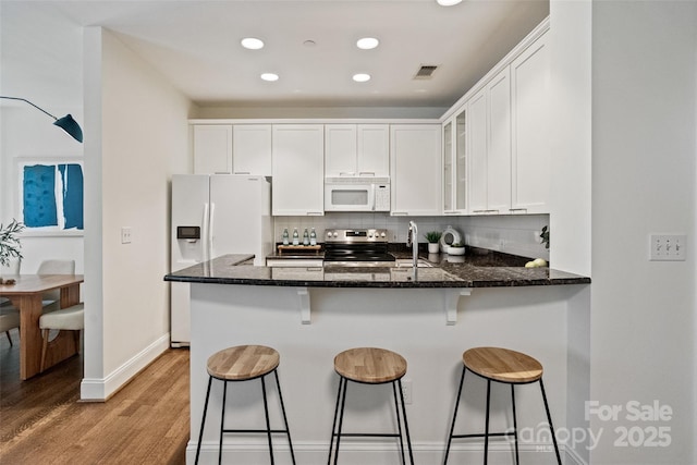 400 N Church St Unit 226, Charlotte, NC 28202 - kitchen featuring white appliances, light wood-type flooring, glass insert cabinets, tasteful backsplash, and white cabinetry