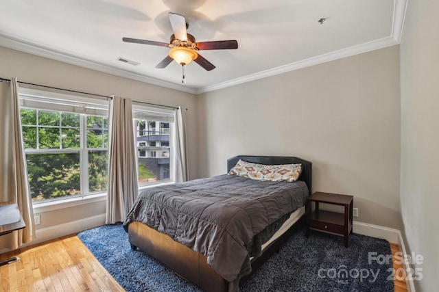 bedroom featuring hardwood / wood-style flooring, crown molding, baseboards, and a ceiling fan