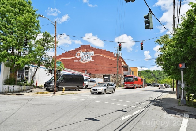 view of asphalt street featuring traffic lights, sidewalks, street lights, curbs, and traffic signs