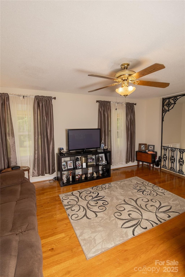 living area featuring a ceiling fan, wood finished floors, and healthy amount of natural light