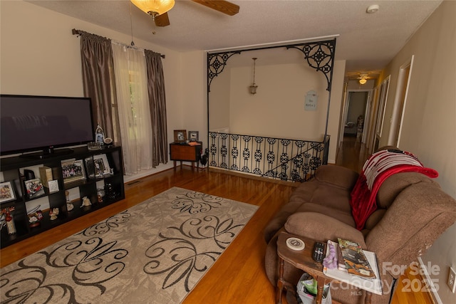 living room with a ceiling fan, wood finished floors, and a textured ceiling