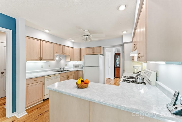 kitchen with white appliances, light brown cabinets, a peninsula, ceiling fan, and light countertops