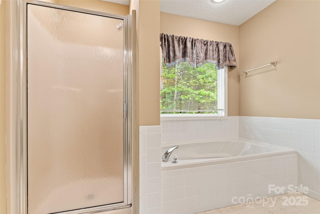 full bathroom with a bath, a shower stall, and a textured ceiling