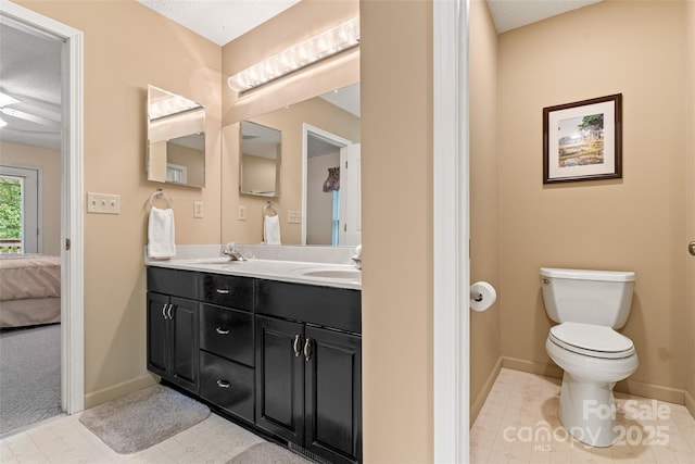 full bathroom with toilet, double vanity, connected bathroom, baseboards, and tile patterned flooring