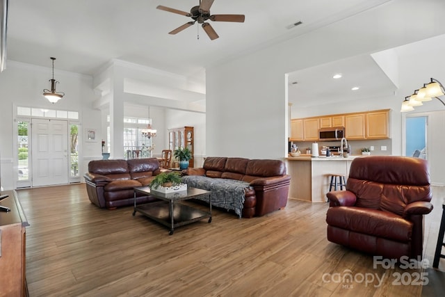 146 Burtons Barn Rd, Mooresville, NC 28115 - living room with a towering ceiling, wood finished floors, a ceiling fan, a chandelier, and ornamental molding