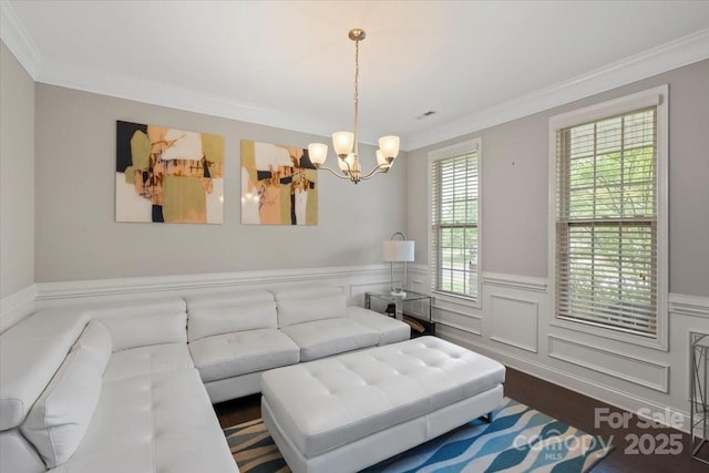 living area featuring a chandelier, ornamental molding, and wainscoting