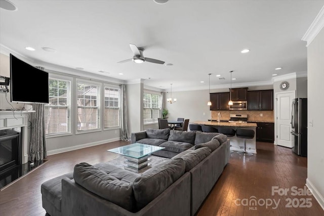 living area featuring ornamental molding, ceiling fan, recessed lighting, dark wood-type flooring, and baseboards