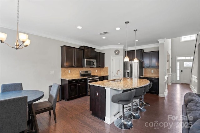 kitchen featuring stainless steel appliances, a sink, dark wood-style floors, a chandelier, and a breakfast bar