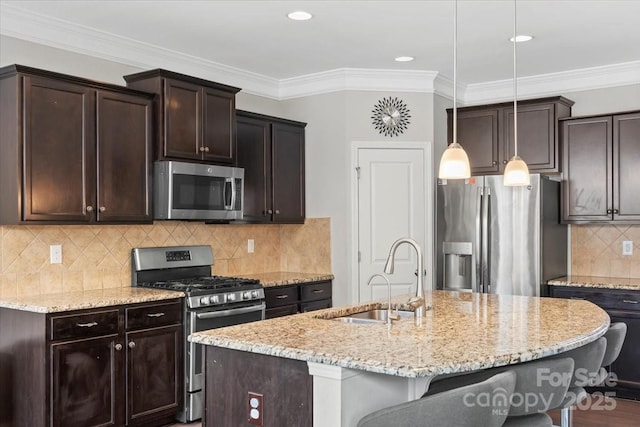 kitchen with appliances with stainless steel finishes, a sink, a kitchen bar, dark brown cabinets, and light stone countertops