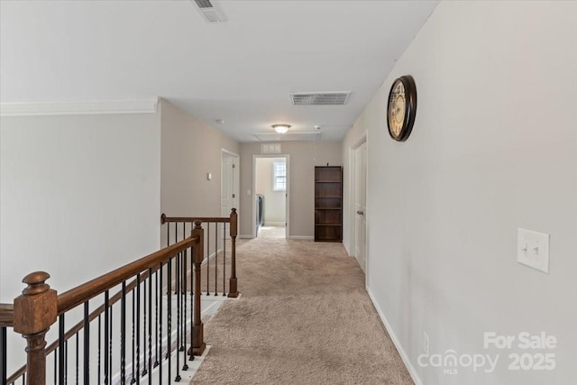 hall with an upstairs landing, attic access, light colored carpet, and baseboards