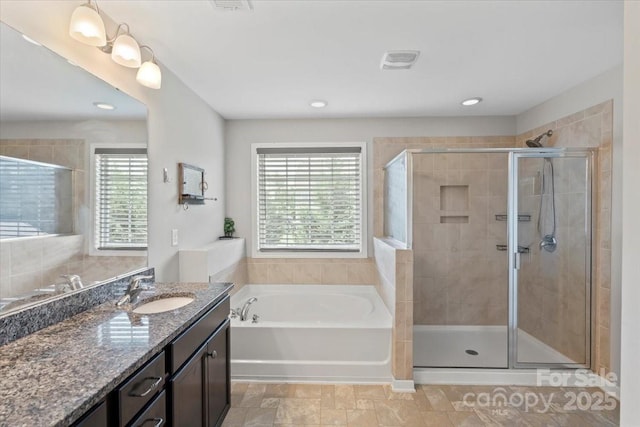 full bathroom featuring a shower stall, a bath, vanity, and recessed lighting