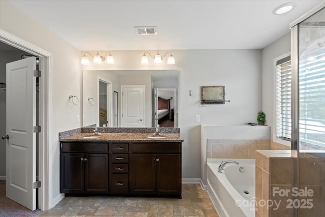 full bath featuring a garden tub, double vanity, and baseboards