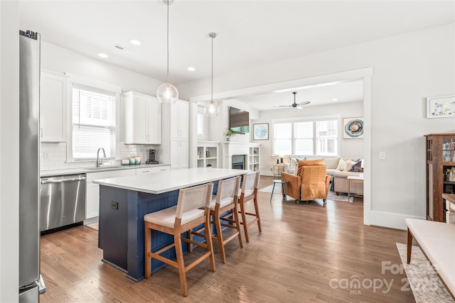 5210 Kelly St, Charlotte, NC 28205 - kitchen with stainless steel dishwasher, a sink, ceiling fan, wood finished floors, and backsplash