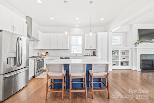 5210 Kelly St, Charlotte, NC 28205 - kitchen featuring appliances with stainless steel finishes, wall chimney range hood, plenty of natural light, light wood-style flooring, and recessed lighting