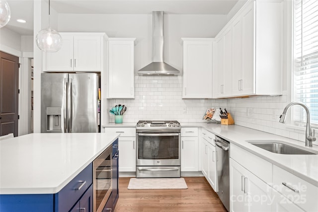 5210 Kelly St, Charlotte, NC 28205 - kitchen featuring appliances with stainless steel finishes, a sink, wall chimney range hood, blue cabinetry, and light countertops