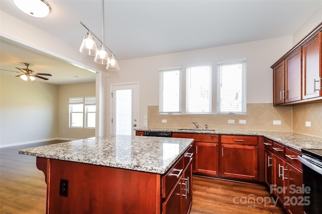 kitchen with a sink, reddish brown cabinets, a kitchen island, dark wood finished floors, and ceiling fan