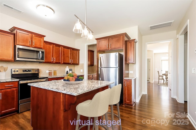 kitchen featuring appliances with stainless steel finishes, decorative backsplash, dark wood finished floors, and a center island