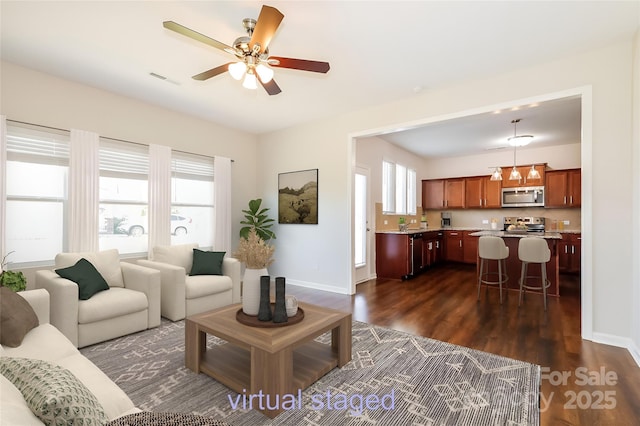 living area with healthy amount of natural light, dark wood-style floors, a ceiling fan, and baseboards
