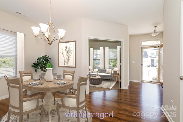 dining area featuring dark wood-type flooring, a chandelier, and baseboards
