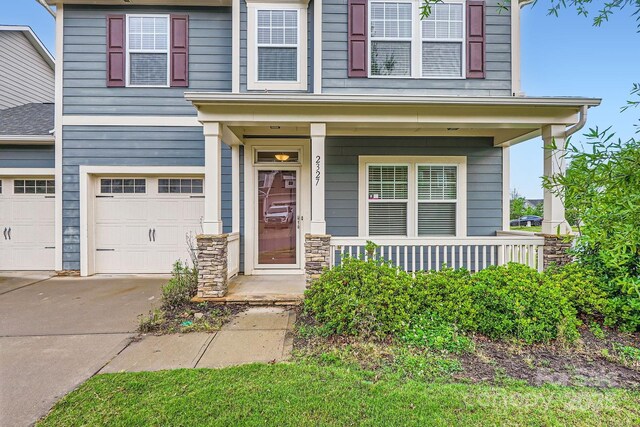 2327 Glenway Trail Ct, Pineville, NC 28134 - view of front of house featuring driveway, an attached garage, a porch, and stone siding