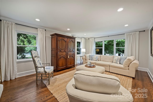 living area featuring healthy amount of natural light, recessed lighting, baseboards, dark wood finished floors, and crown molding