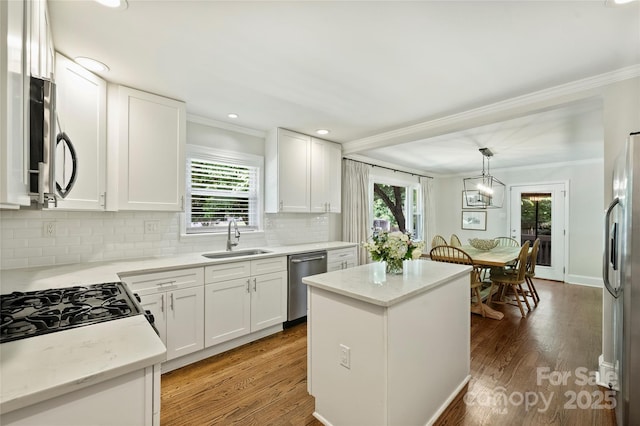 kitchen featuring appliances with stainless steel finishes, ornamental molding, a sink, tasteful backsplash, and plenty of natural light