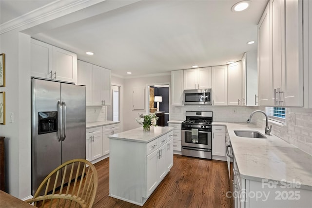 kitchen with stainless steel appliances, a sink, decorative backsplash, white cabinetry, and light stone counters