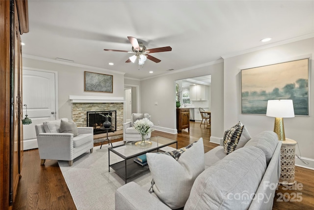 living area featuring a ceiling fan, wood finished floors, a stone fireplace, recessed lighting, and baseboards