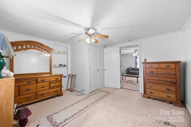 bedroom featuring a textured ceiling, carpet floors, ornamental molding, and a ceiling fan