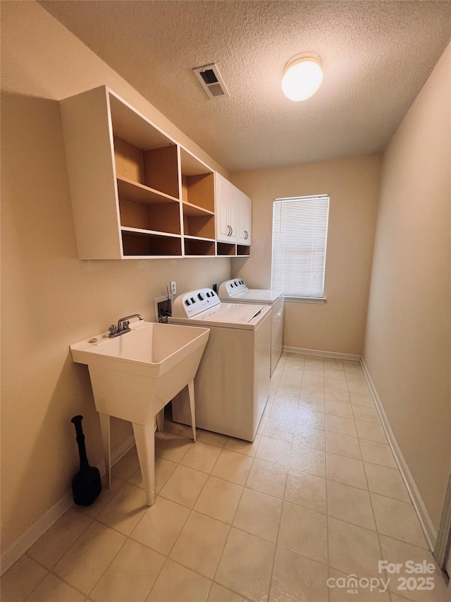 318 Linsbury Ct, Gastonia, NC 28056 - laundry area featuring cabinet space, separate washer and dryer, a textured ceiling, baseboards, and light tile patterned floors