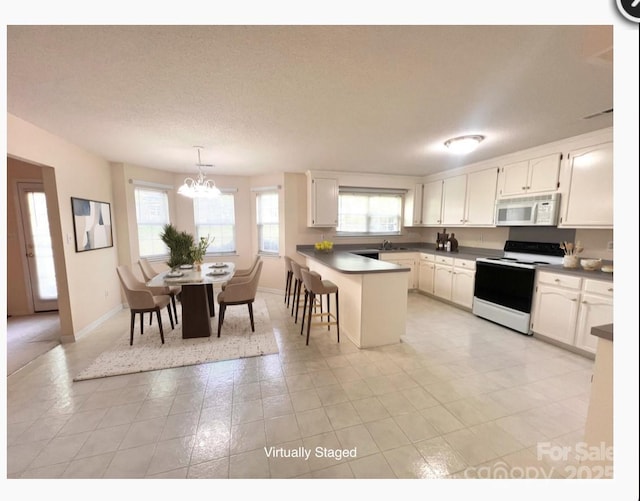 318 Linsbury Ct, Gastonia, NC 28056 - kitchen featuring white appliances, a peninsula, white cabinets, a chandelier, and a breakfast bar area