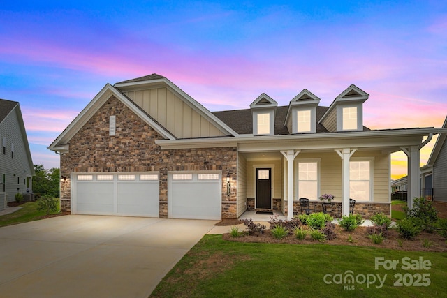 view of front of house with driveway, stone siding, a porch, board and batten siding, and an attached garage