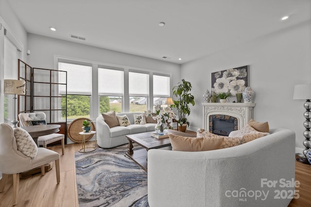 living room with a premium fireplace, wood finished floors, and recessed lighting