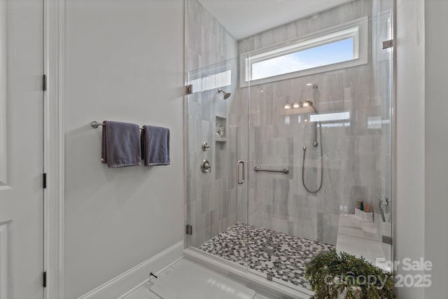 full bath with a stall shower, baseboards, and marble finish floors