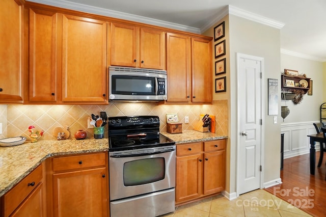 541 River Park Rd, Belmont, NC 28012 - kitchen with appliances with stainless steel finishes, ornamental molding, brown cabinetry, light stone counters, and tasteful backsplash