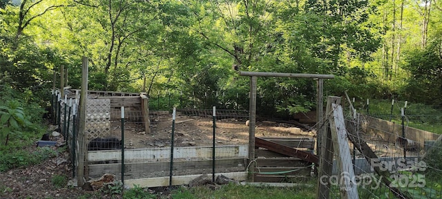 7881 Us-25/70 Hwy, Marshall, NC 28753 - gate featuring a wooded view and a vegetable garden