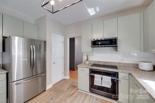 kitchen featuring black appliances, light wood finished floors, backsplash, gray cabinetry, and baseboards