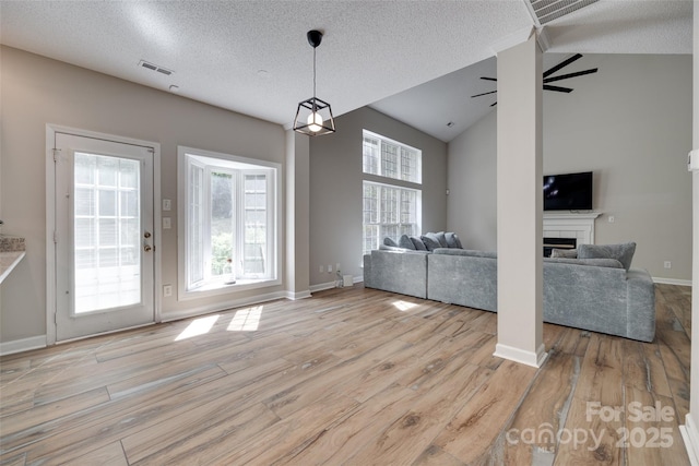dining area with a textured ceiling, plenty of natural light, light wood-style floors, vaulted ceiling, and baseboards